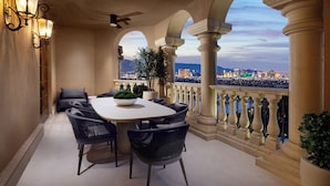 A balcony with a dining table, chairs, and a view of a cityscape.