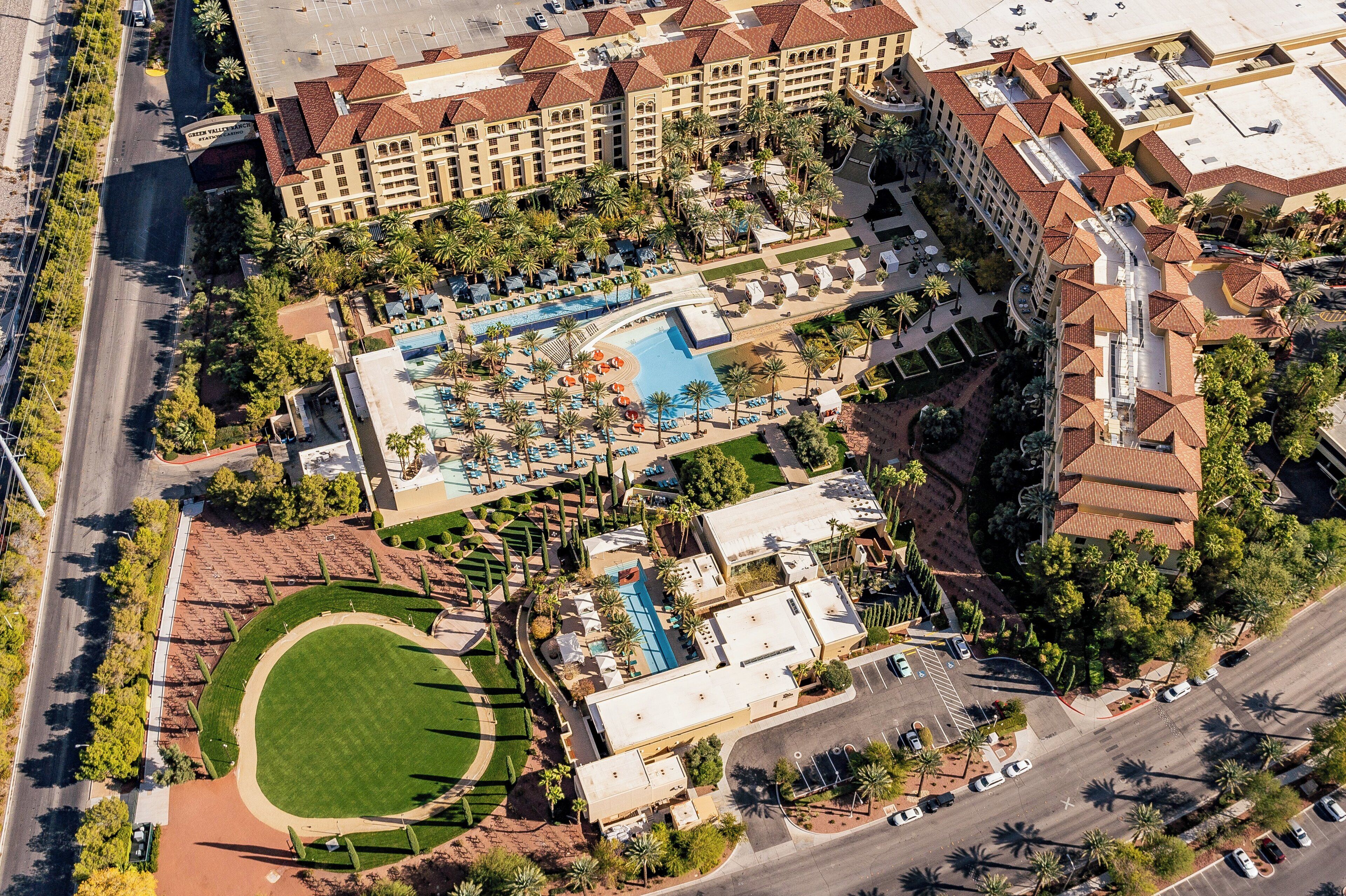 Vista aérea de um hotel com vários edifícios, piscina e áreas ajardinadas.