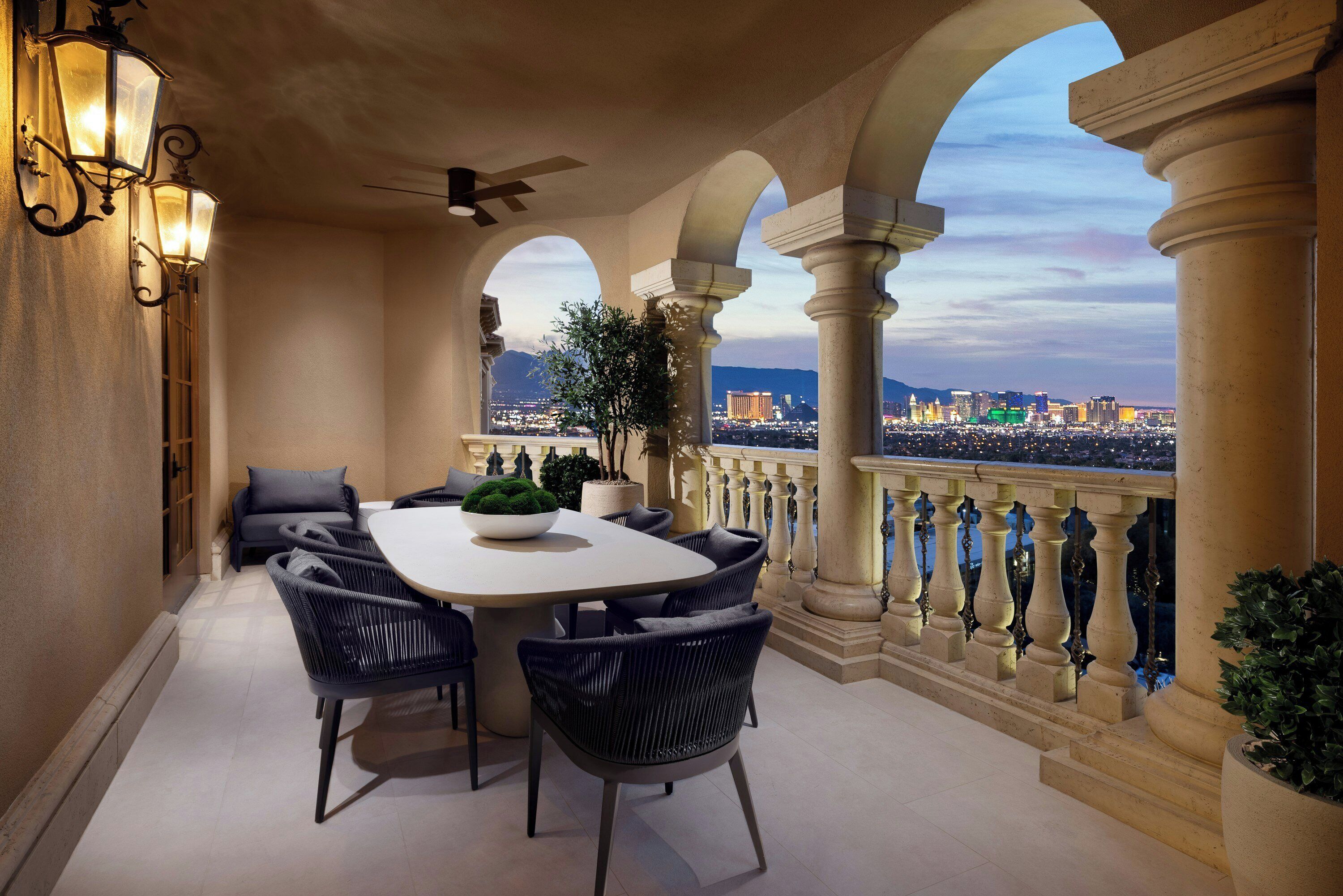 A balcony with a dining table, chairs, and a potted plant.
