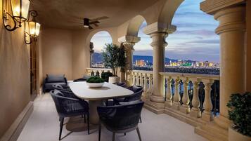 A balcony with a dining table, chairs, and a potted plant.