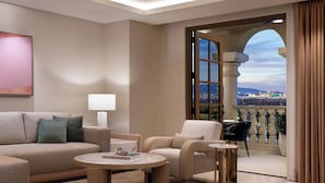 A modern living room with a sofa, armchairs, a coffee table, and a view of a cityscape through a large window.