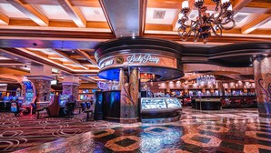 A casino interior with slot machines, a Lucky Penny sign, and a chandelier.