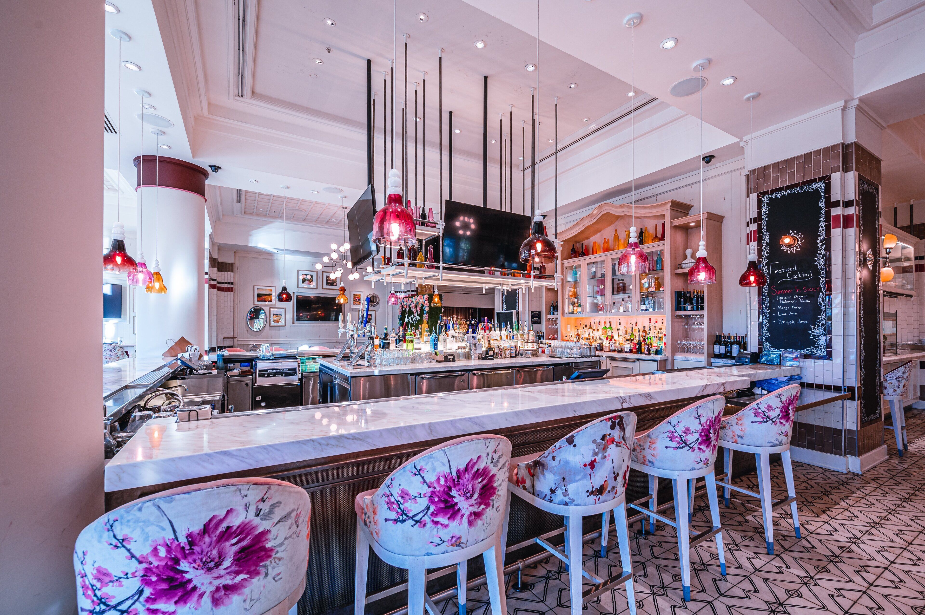 A bar area with a long counter, bar stools, and a television screen.