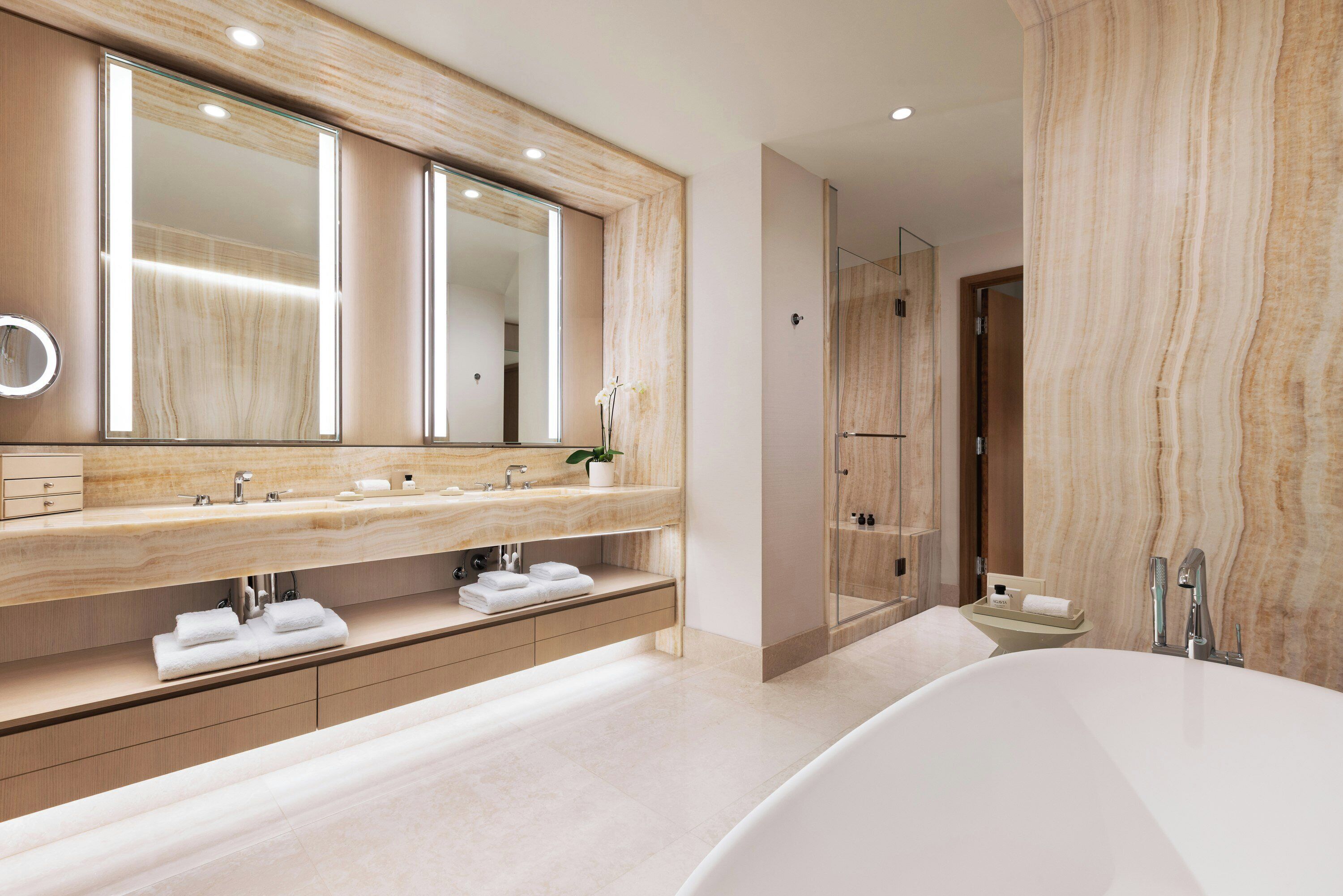 A modern bathroom with a large mirror, a freestanding bathtub, and a glass-enclosed shower area.