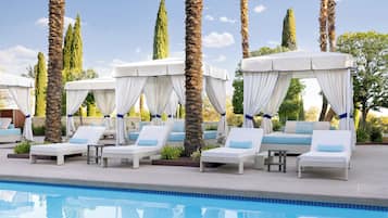 Una piscina al aire libre, camas de piscina con cargo, sombrillas