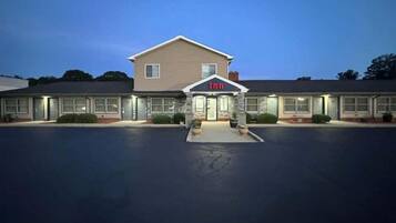 A two-story motel with a central entrance and a parking lot.