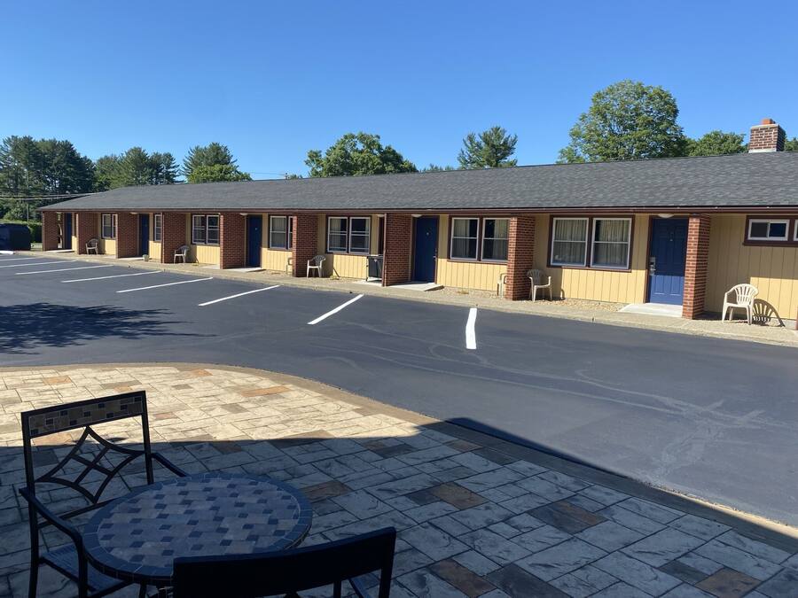 Ein Motel mit Parkplatz, Außenbereich mit Sitzgelegenheiten und einer Ziegel-Fassade.
