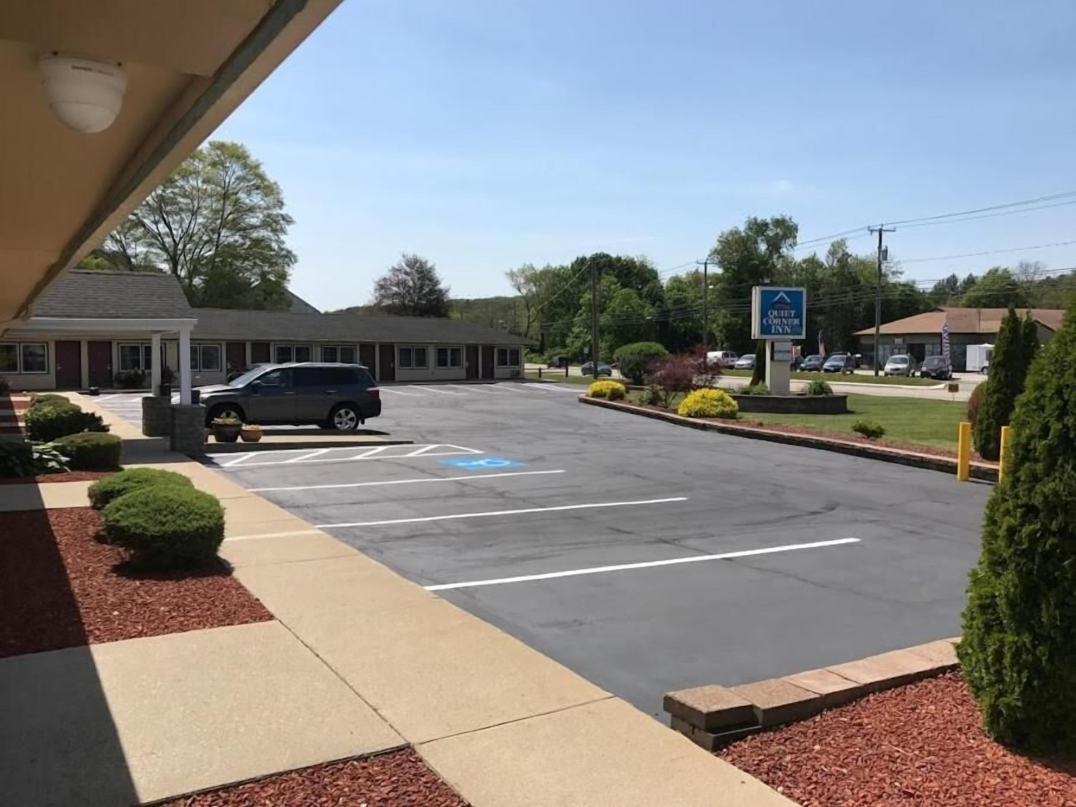 Un parcheggio con un posto auto riservato disabili blu, un edificio con il cartello 'OUTLET COUNTRY Inn' e un cielo sereno.