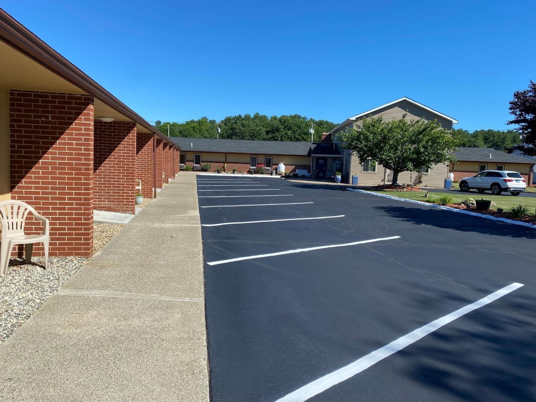 A motel with a row of rooms, a parking lot, and a small garden area.