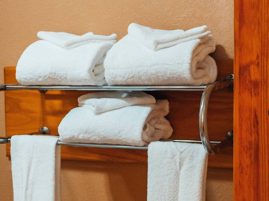 A metal towel rack with white and beige towels folded neatly.