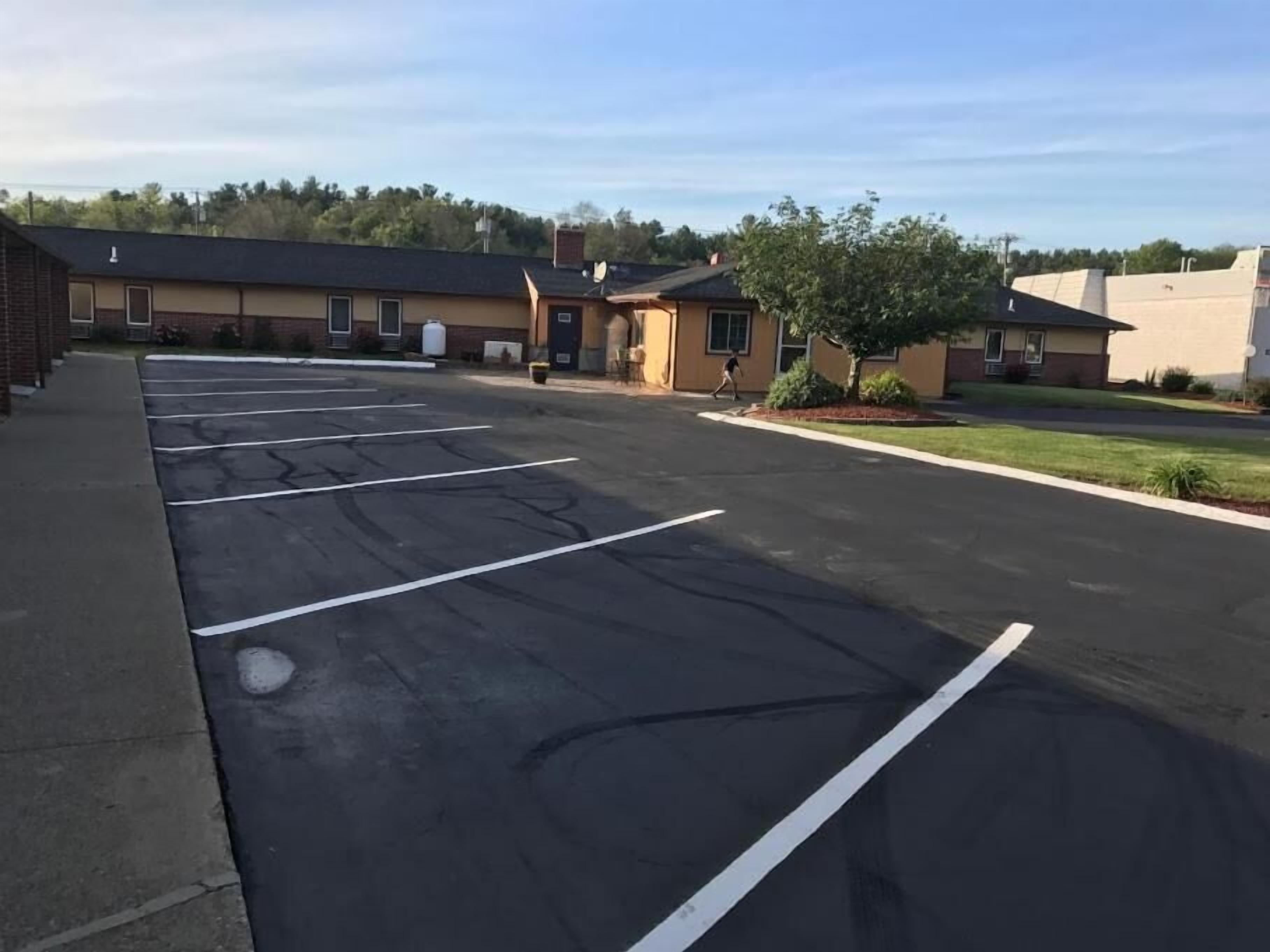 A parking lot with marked spaces, a building with a brick facade, and a clear sky.
