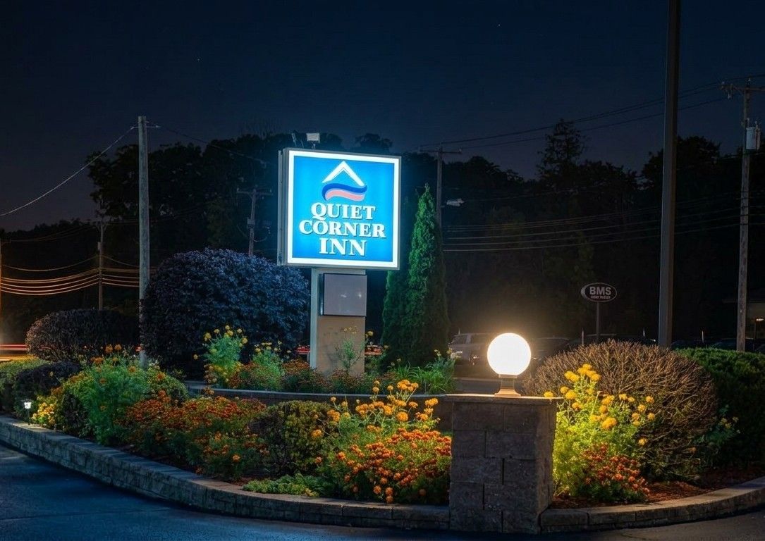 Schild für das Quiet Corner Inn bei klarem Nachthimmel, beleuchtet.