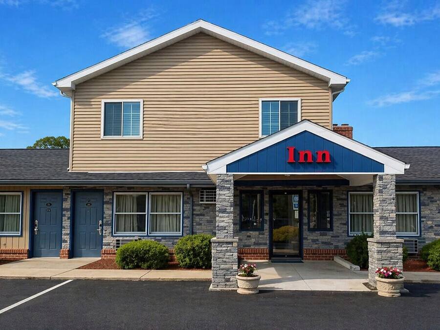 A two-story motel with a prominent 'Inn' sign, stone facade, and a parking lot.