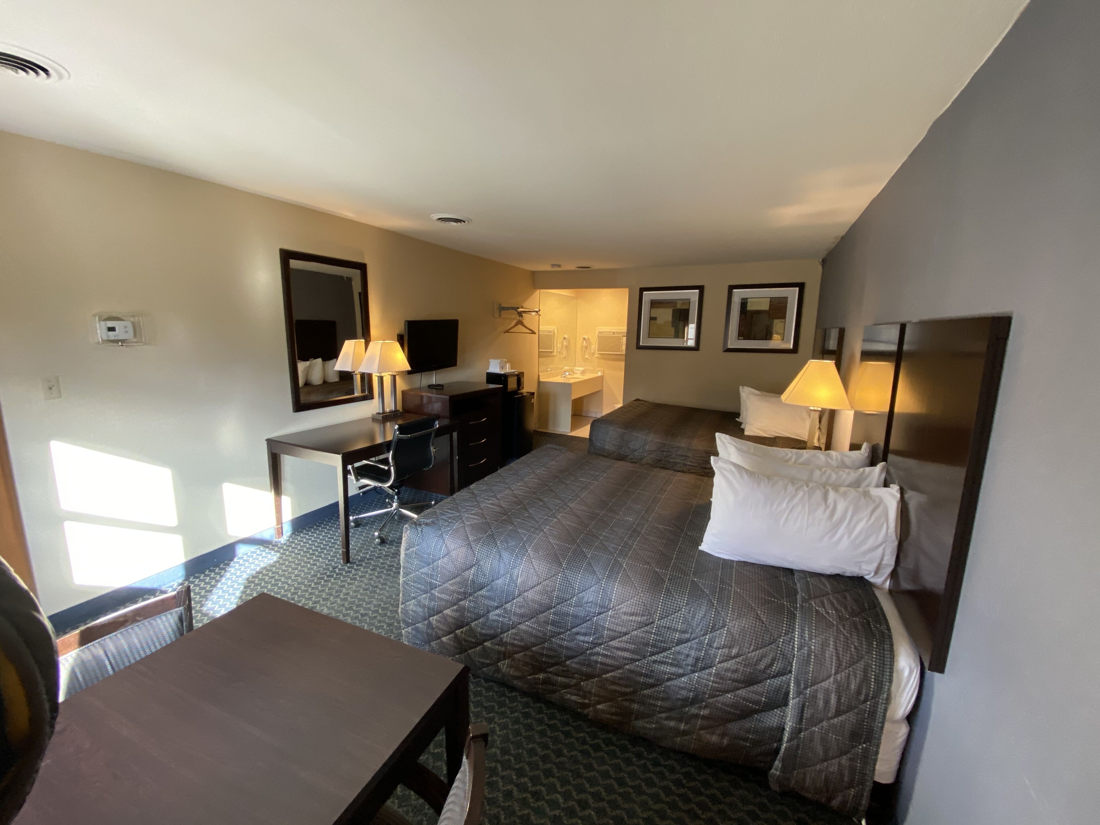 A hotel room with a bed, desk, chair, and a bathroom.