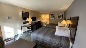 A hotel room with a bed, desk, chair, and a bathroom.