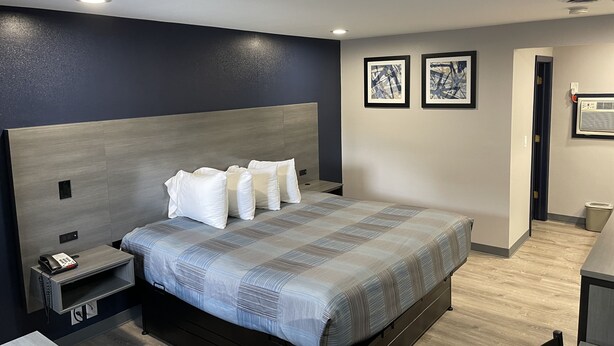 A modern hotel room with a large bed, a bedside table with a phone, and a small desk. - Golden Hill Inn Danbury (Danbury)