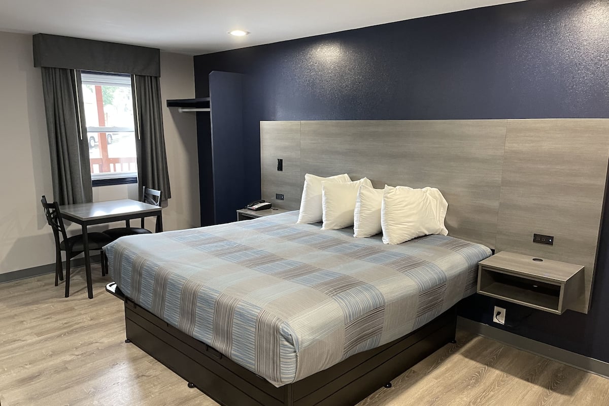 A hotel room with a large bed, bedside tables, a desk, and a chair.