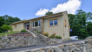 A two-story stone house with a stone staircase leading to the entrance, surrounded by a landscaped garden with colorful flowers. - Golden Hill Inn Danbury (Danbury)