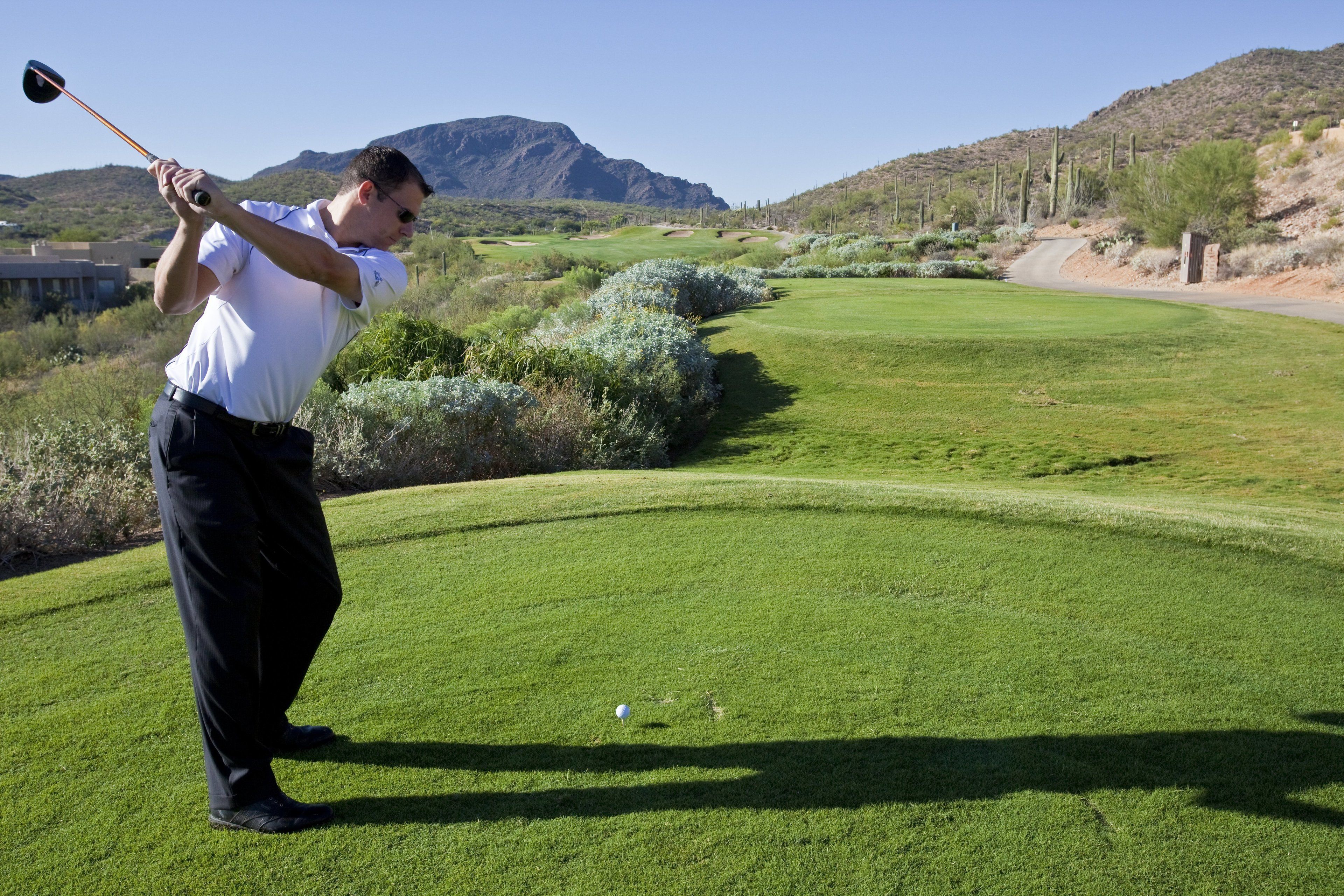 A golf course with a clear view of the green, a tee box, and a distant mountain.