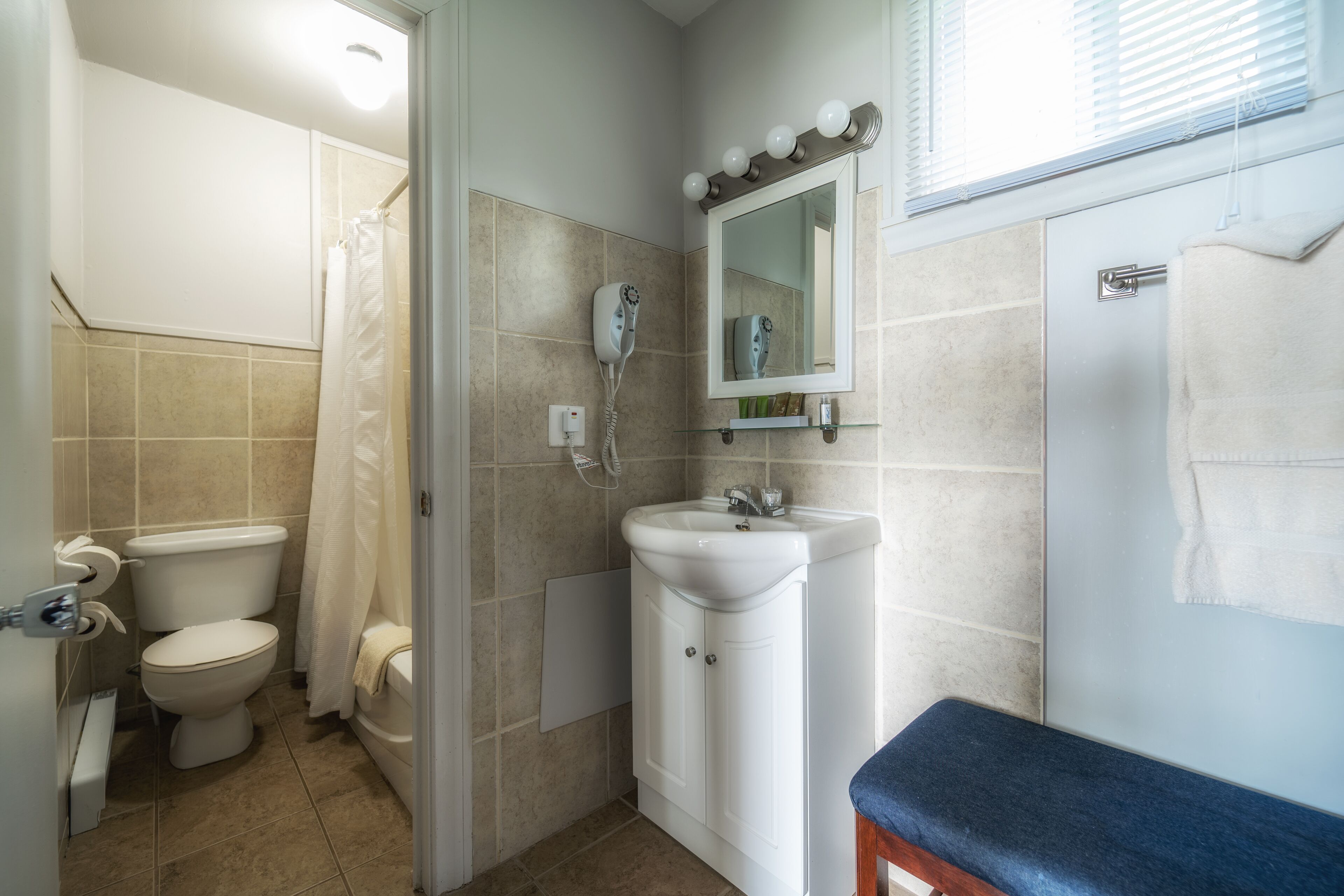 A bathroom with a toilet, shower, sink, and mirror.