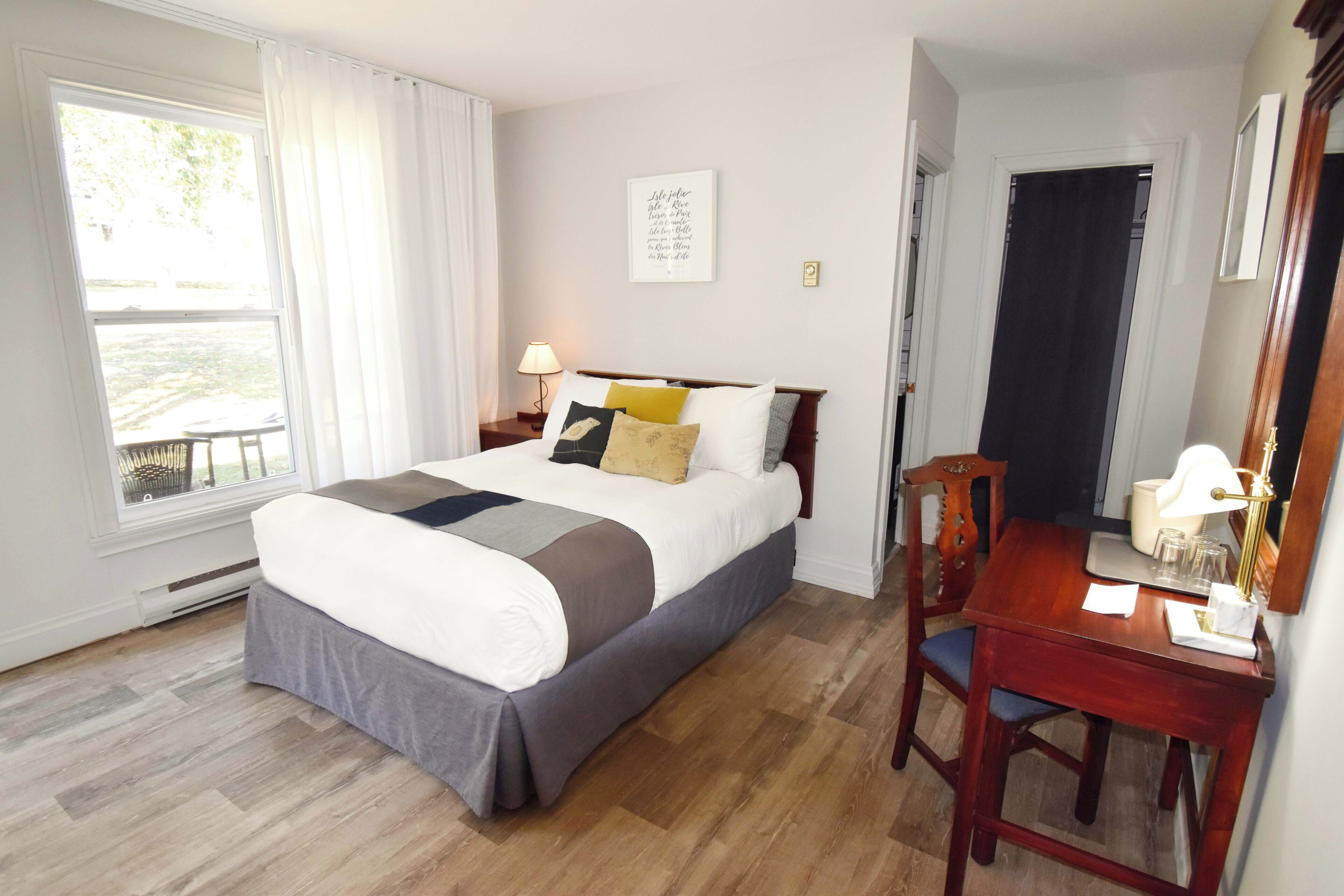 A bedroom with a bed, bedside table, chair, and a window with curtains.