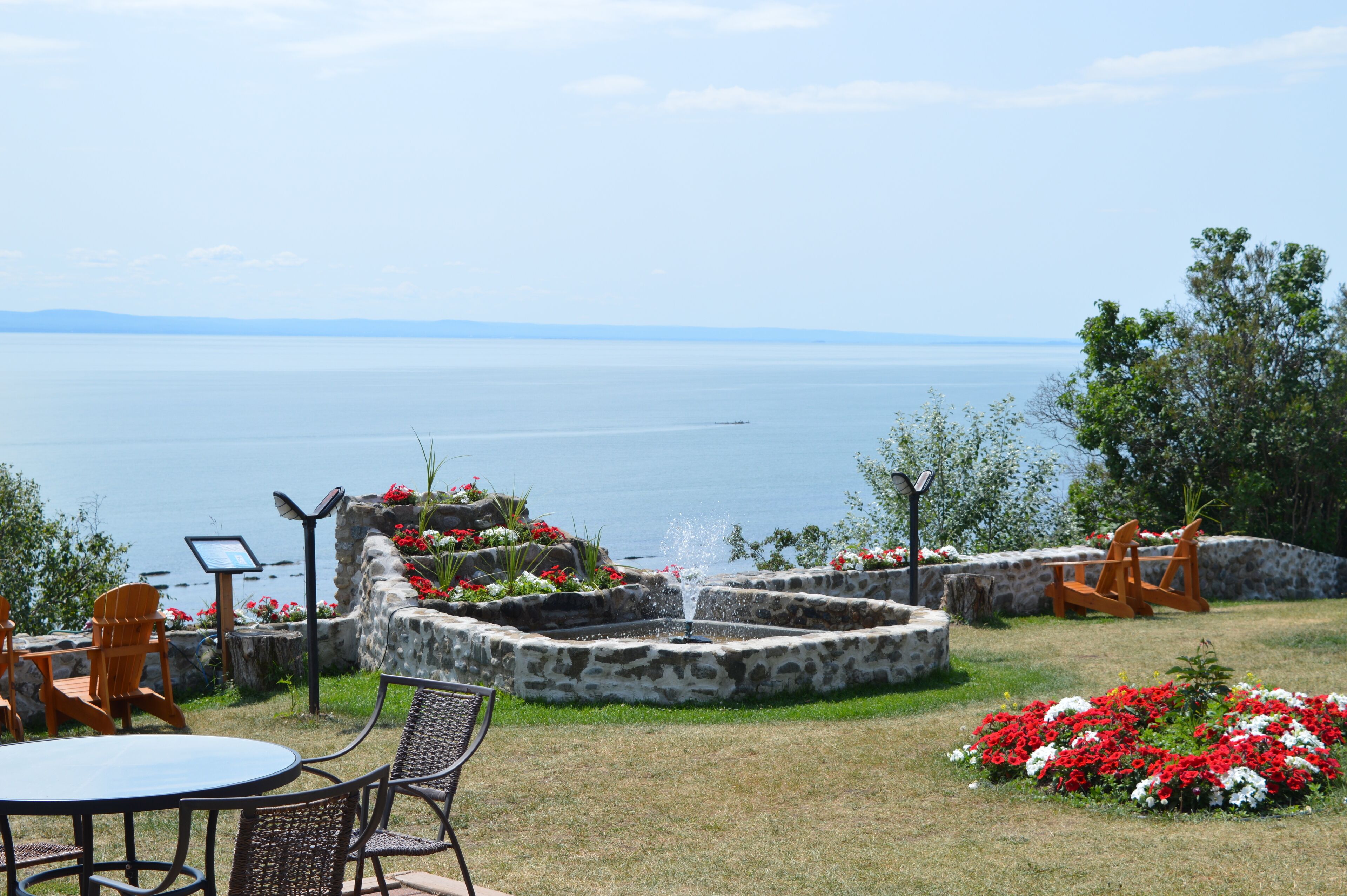 A patio with a stone fountain, outdoor seating, and a view of the water.