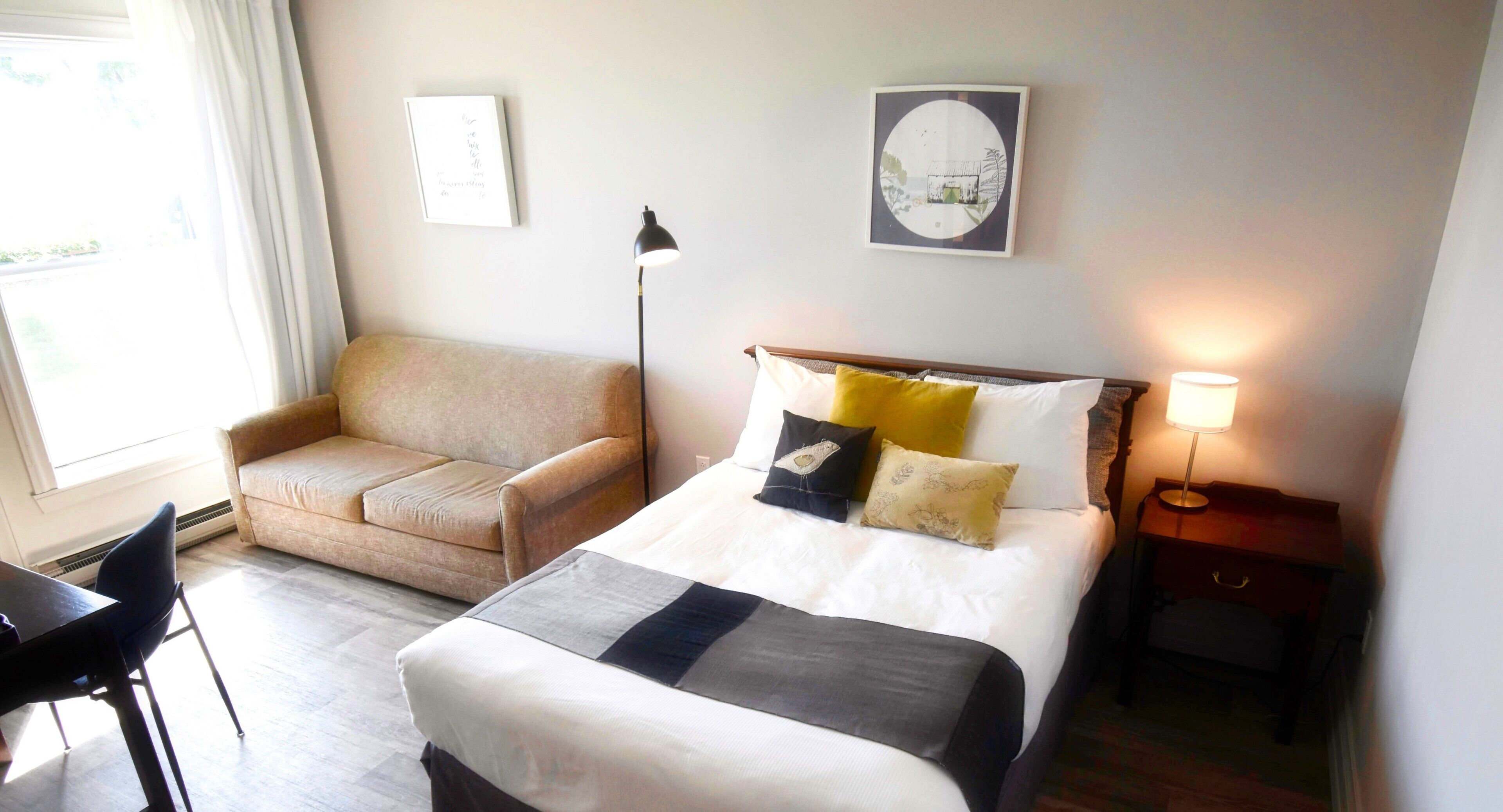 A hotel room with a bed, a sofa, a desk, and a nightstand.