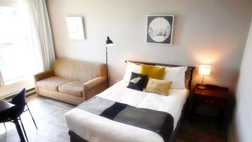 A hotel room with a bed, a sofa, a desk, and a nightstand.