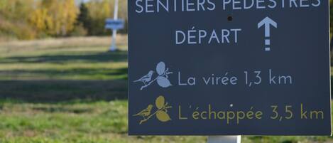 Um sinal com indicações e distâncias para trilhas de caminhada.