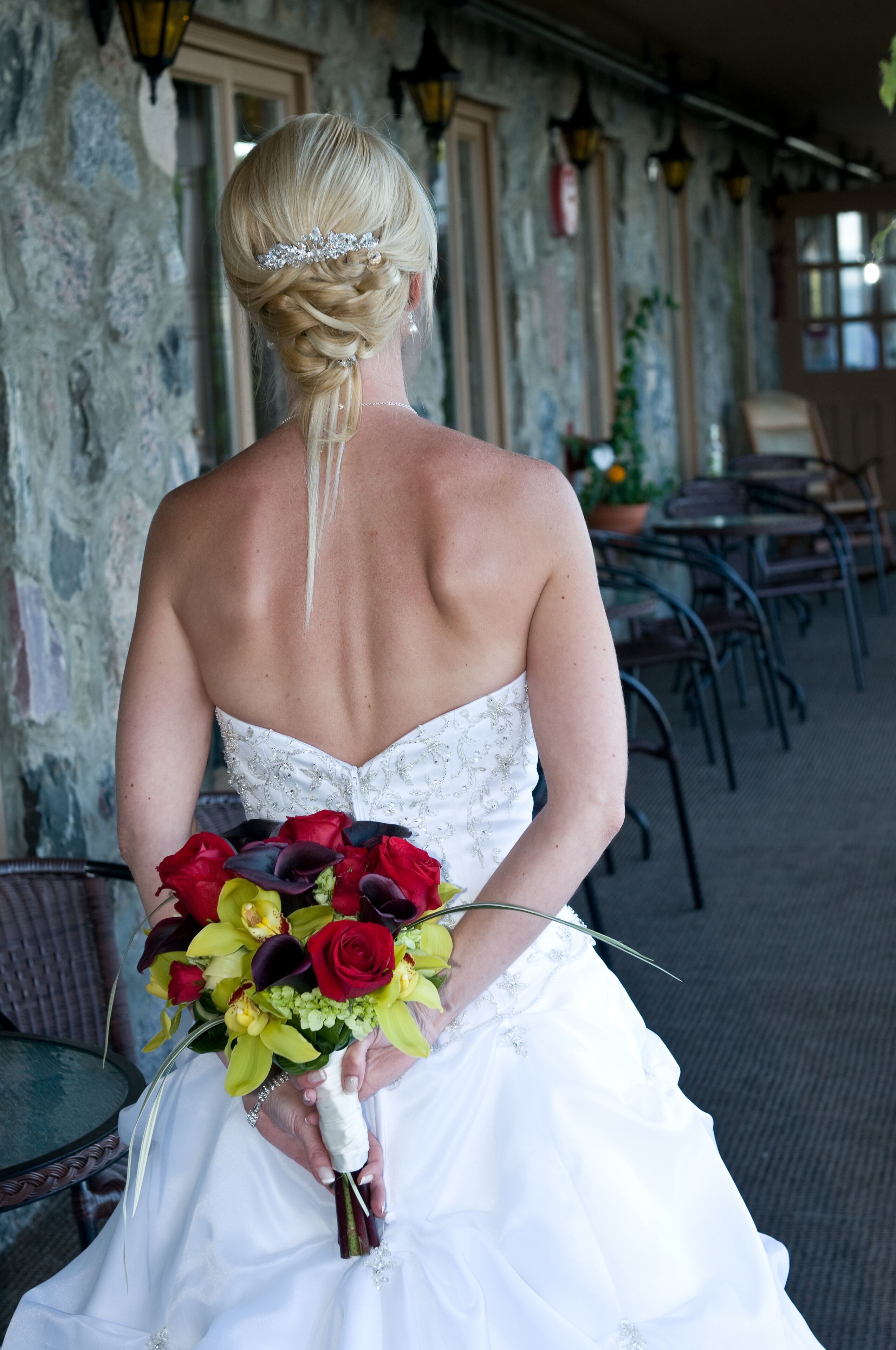 A wedding dress with a strapless back and a bouquet of red and yellow flowers.