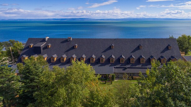 A large building with multiple small attached structures, likely guest rooms, overlooking a large body of water.