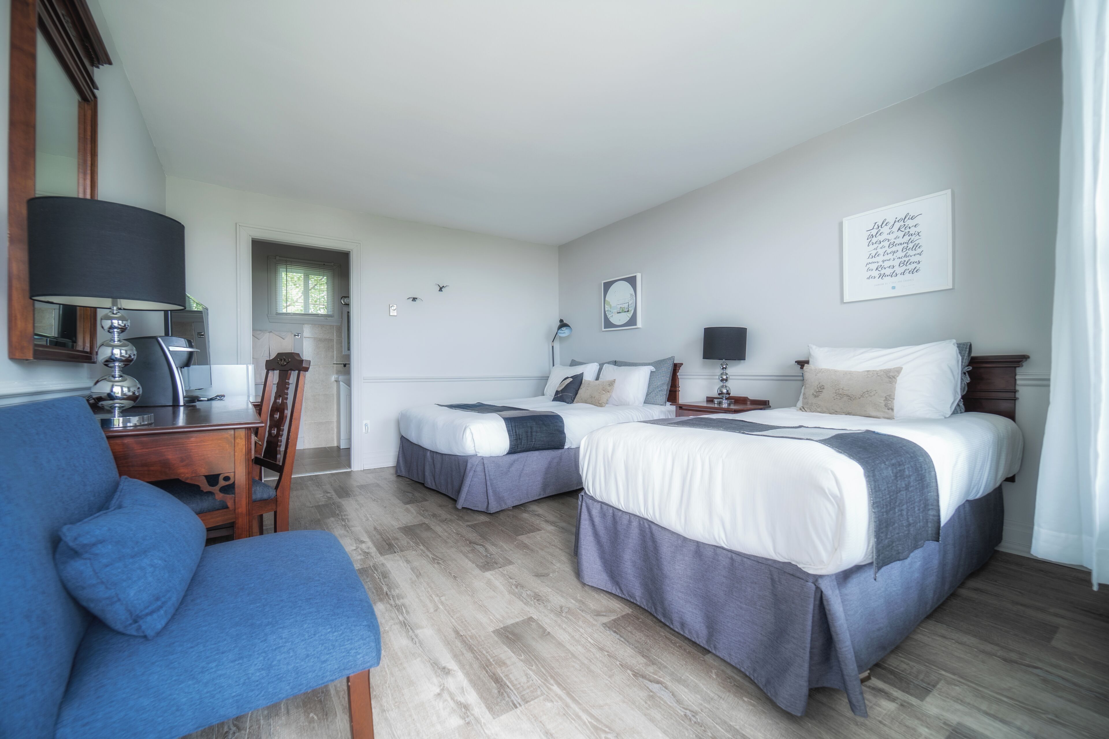 Une chambre d’hôtel avec deux lits, un bureau et une chaise.