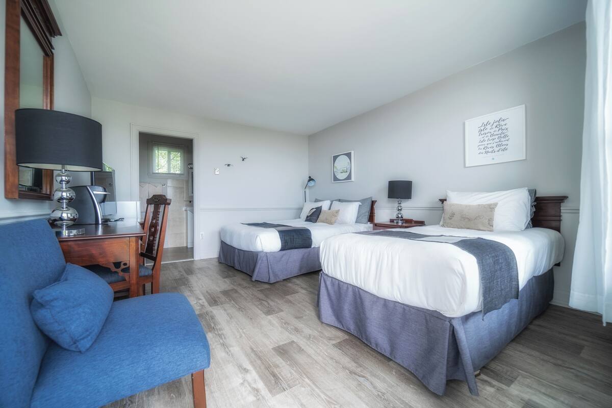 Een hotelkamer met twee bedden, een bureau en een stoel.
