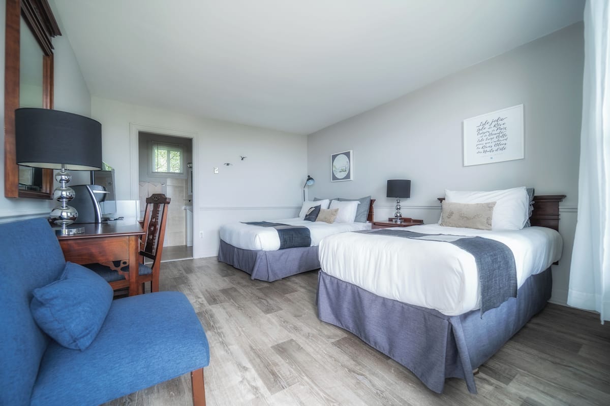 Une chambre d’hôtel avec deux lits, un bureau et une chaise.