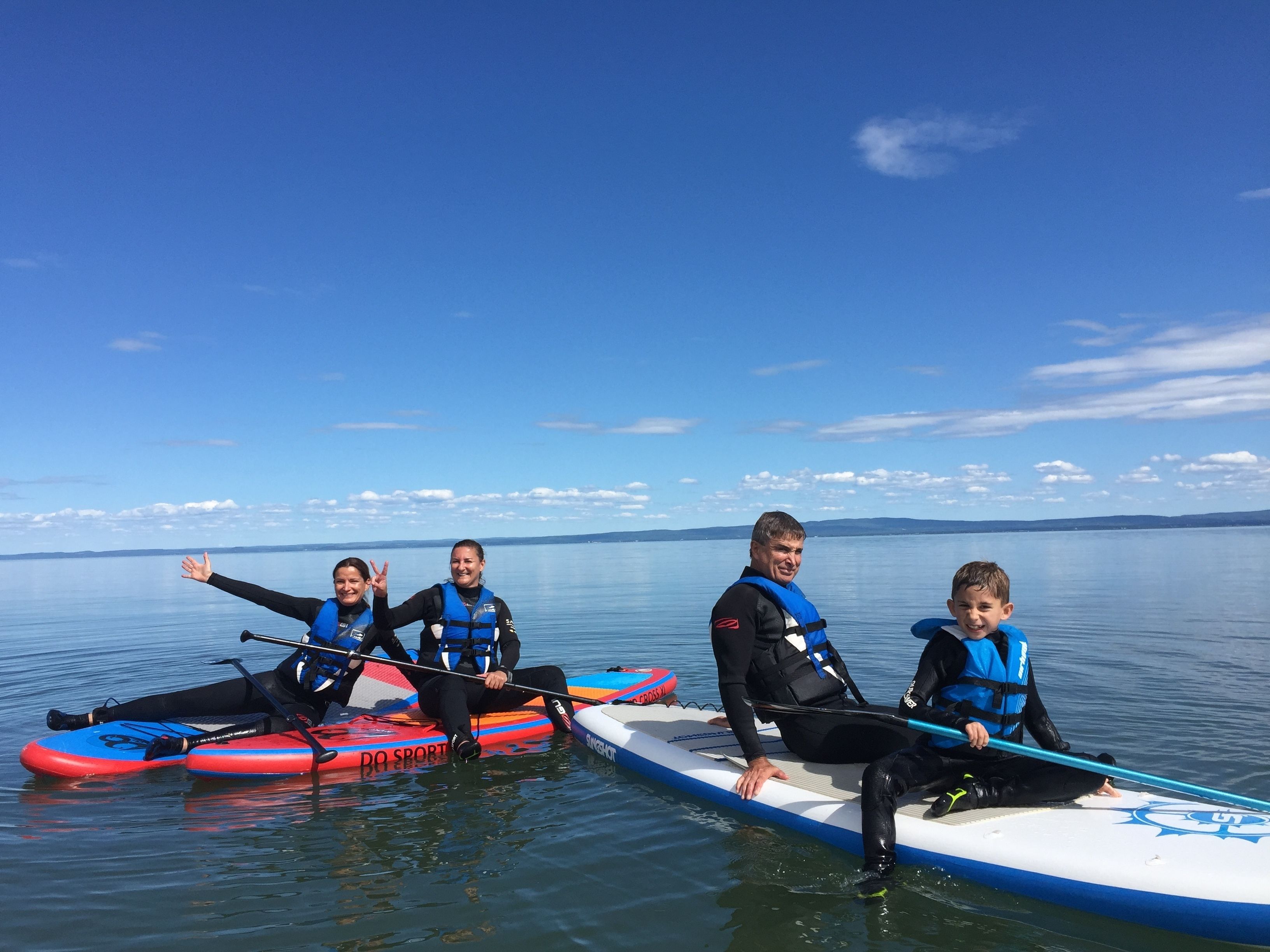 A group of people on paddleboards in a calm body of water with a clear sky.