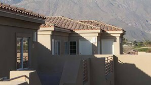 A residential building with a tiled roof, a garage, and a view of snow-capped mountains in the background. - Raintree's Cimarron Golf Resort (Cathedral City)
