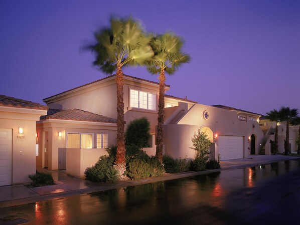 A two-story house with a garage, a covered patio, and a well-maintained lawn.