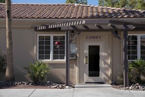A building with a tiled roof, a door labeled "Lobby," and a small outdoor area with rocks and plants.