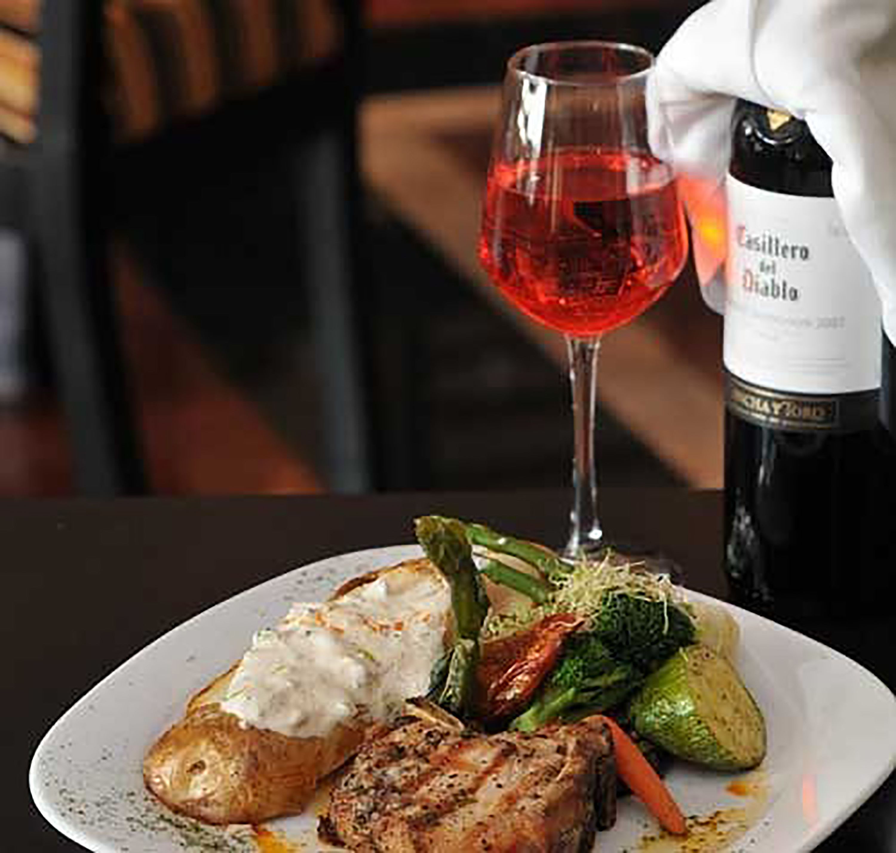 A plate of food with a glass of red wine and a bottle of wine.