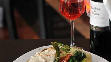 A plate of food with a glass of red wine and a bottle of wine.