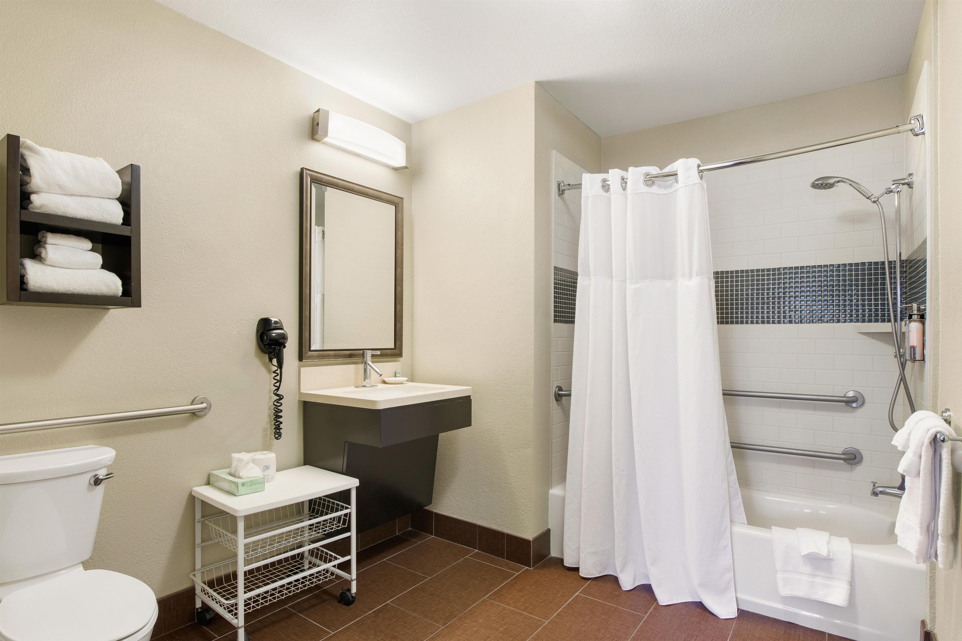 A standard hotel bathroom with a toilet, sink, shower, and a towel rack.
