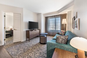 A modern hotel room with a large window, a flat-screen TV, a sofa, and a small round table. - Sonesta ES Suites Anaheim Resort Area (Anaheim)