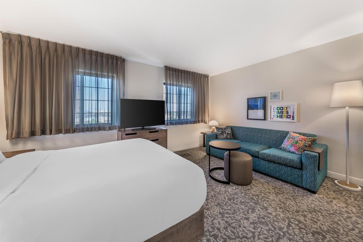 Ein Hotelzimmer mit einem großen Bett, einer Couch, einem Fernseher und einer Lampe.