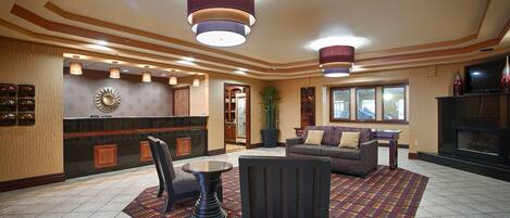 A lobby with a reception desk, seating area, and a fireplace.