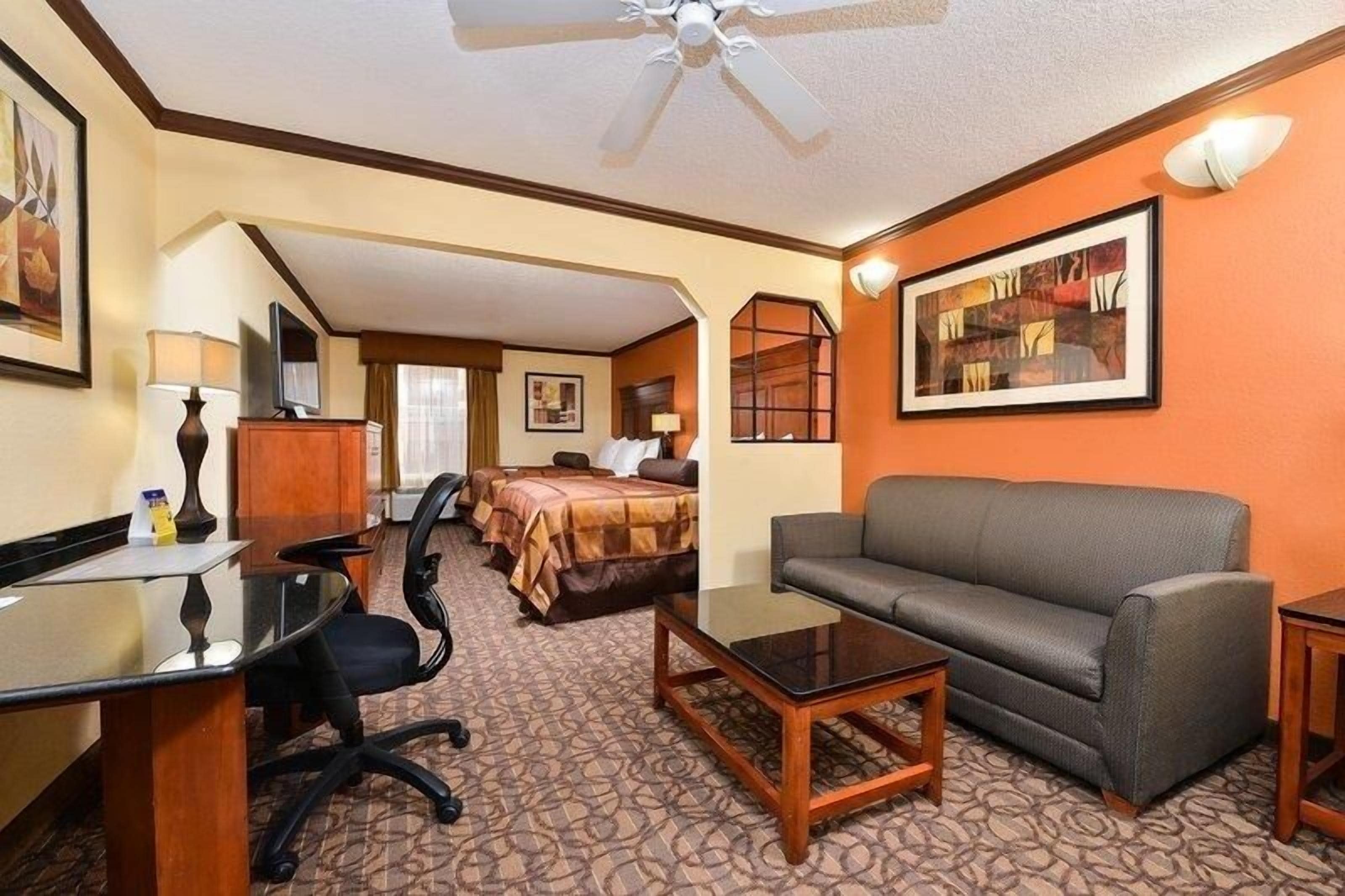 Ein Hotelzimmer mit einer Schlafcouch, einem Schreibtisch mit Stuhl, einem Bett und einem Fernseher.