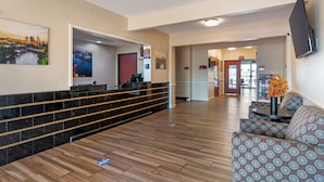 A hotel lobby with a reception desk, seating area, and a TV mounted on the wall.
