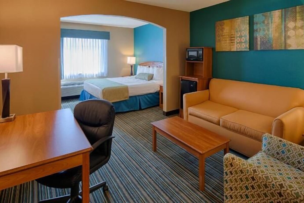A hotel room with a bed, a sofa, a desk, and a television.