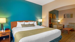 A hotel room with a large bed, two bedside tables with lamps, a chair, a desk, and a small table.