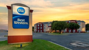 A Best Western hotel sign with a parking lot and buildings in the background.