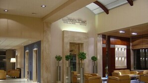 En hotelllobby med en receptionsdisk, en sittgrupp och en skylt som visar att det är ”Royal Post Hotel & Spa”.